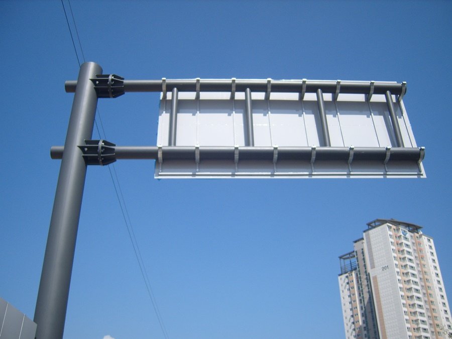 풍하중을 견디도록 튼튼하게 조립된 도로표지판 배면 브라켓과 지주 연결부